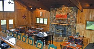 A restaurant with tables and chairs in front of the fireplace.